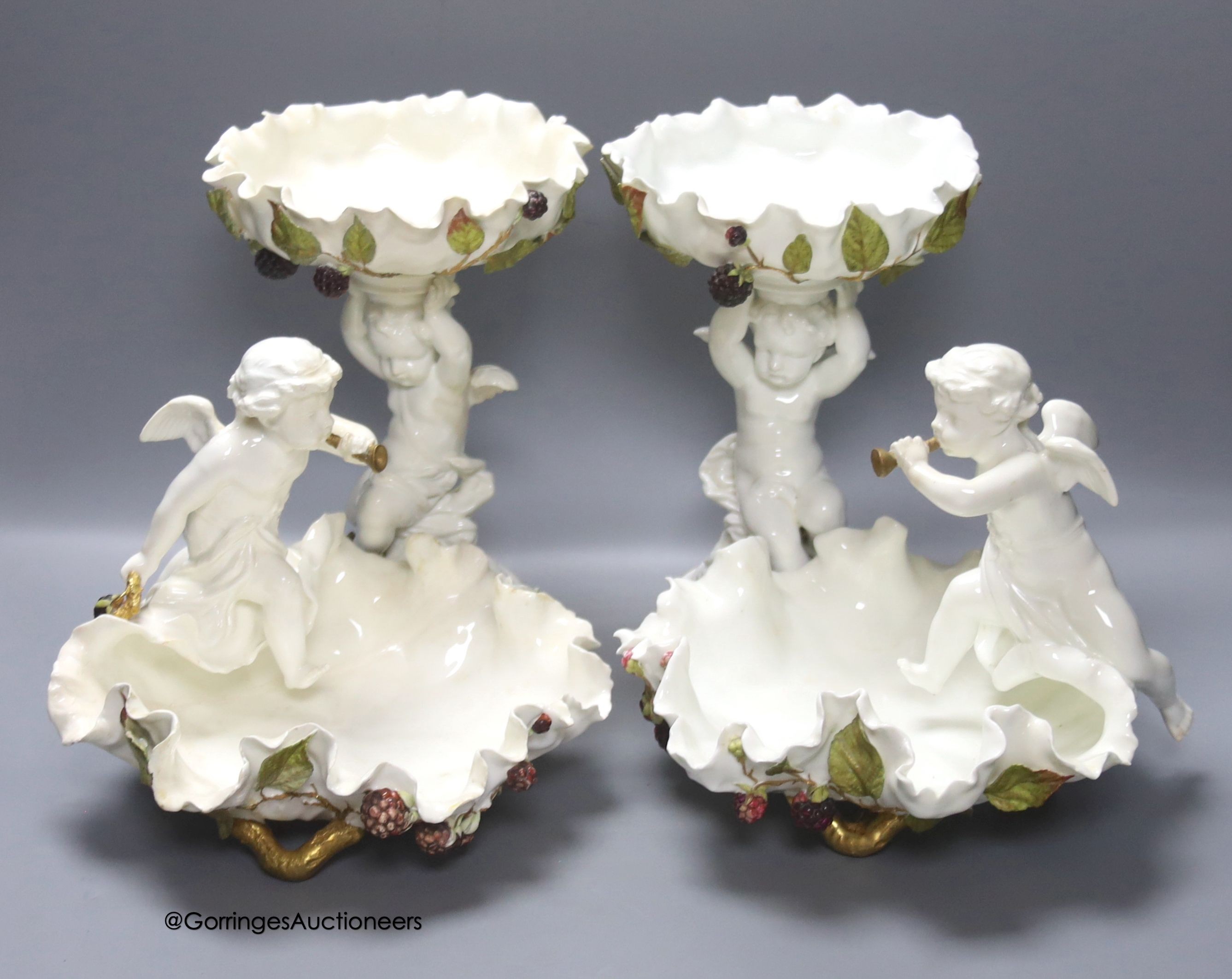 A pair of Moore Bros leaf pattern bowls, encrusted with fruit and surmounted by cherubs and a similar pair of tazza stands, height 24cm